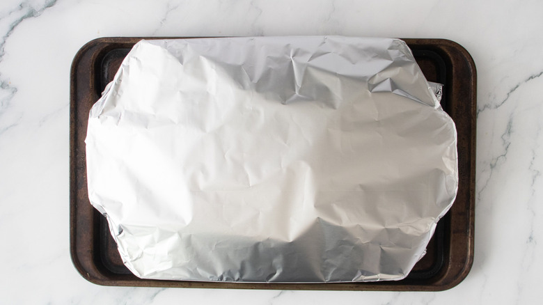 Foil-topped casserole dish on baking sheet