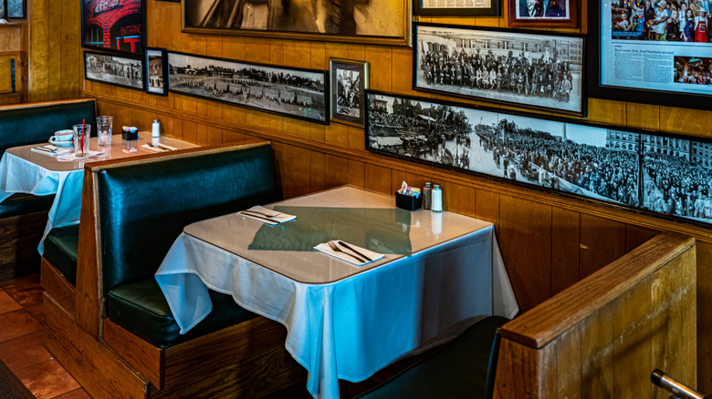 Interior of Italian restaurant with wooden booths and old photos on wall