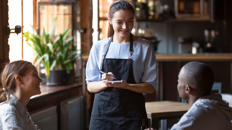Two people at restaurant table talking to waiter