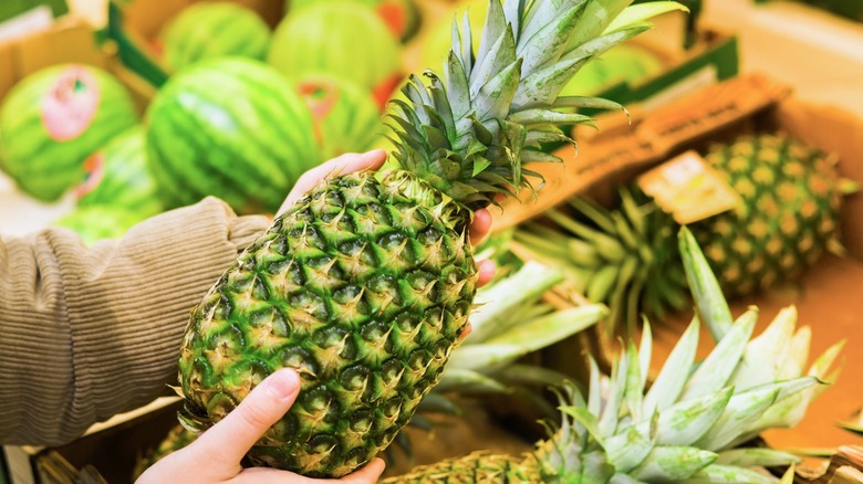Hands holding a pineapple at the supermarket
