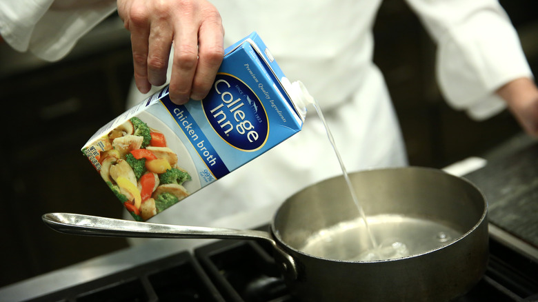 Chef pouring chicken broth into pot 