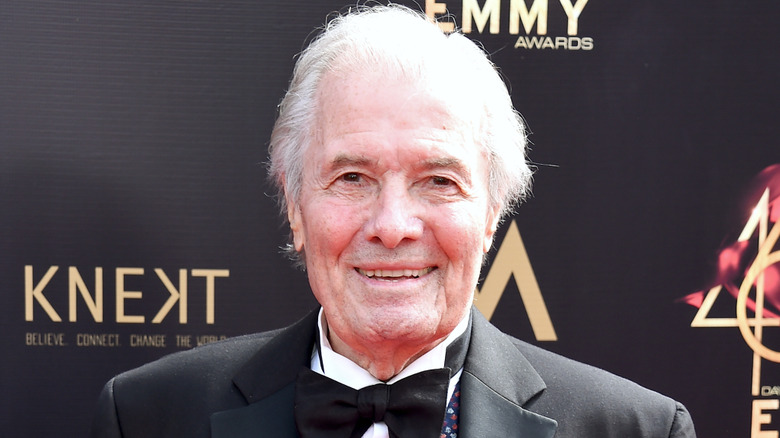 French chef Jacques Pépin wearing a suit and bow tie on black and gold backdrop