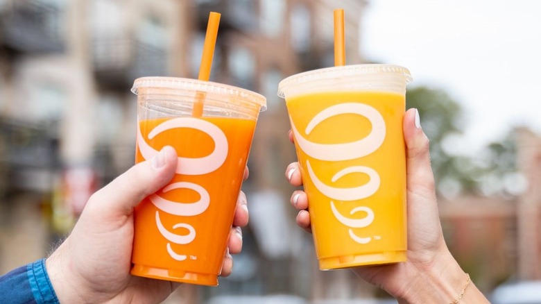 Two people holding orange Jamba smoothies