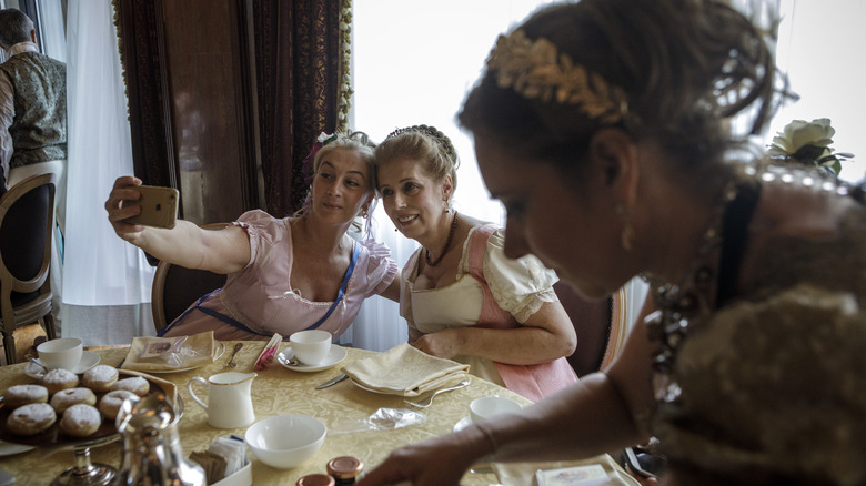 Women dining in vintage attire taking selfie