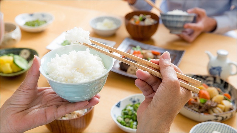 Person holding chopsticks by bowl