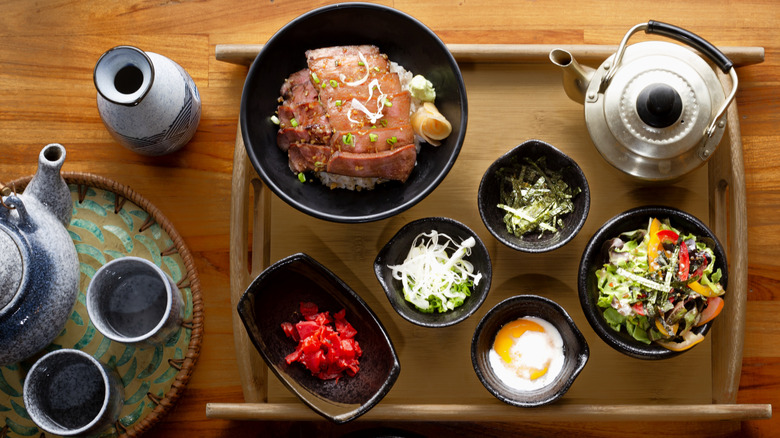 Assorted Japanese foods on tray with tea kettle.