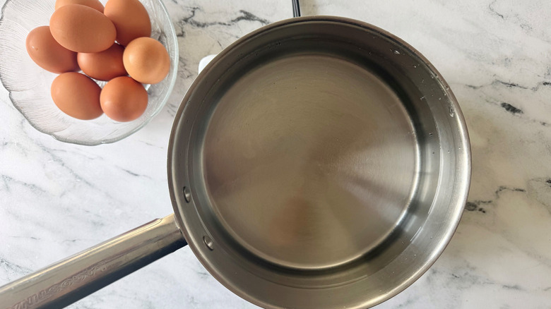 Eggs in bowl next to pot of water