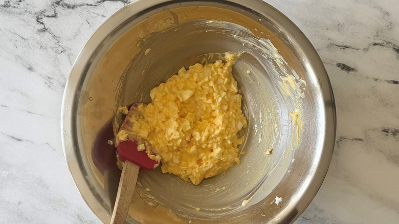 Egg salad with rubber spatula in bowl