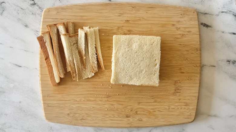 Crusts removed from milk bread on wooden board