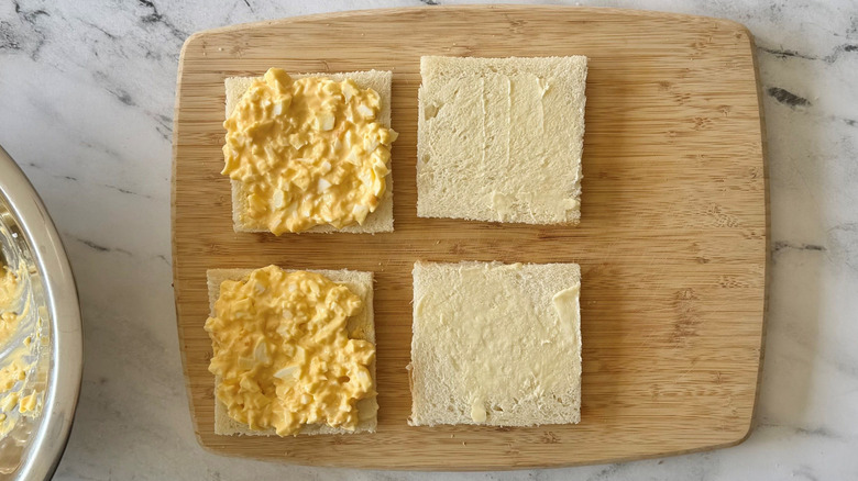 Open faced egg salad sandwiches on wooden board