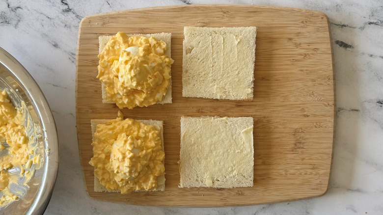 Open faced egg salad sandwiches with whole eggs topped with more egg salad