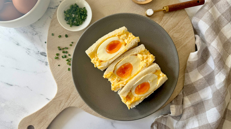 Japanese egg salad sandwiches face up on plate with jammy eggs in middle