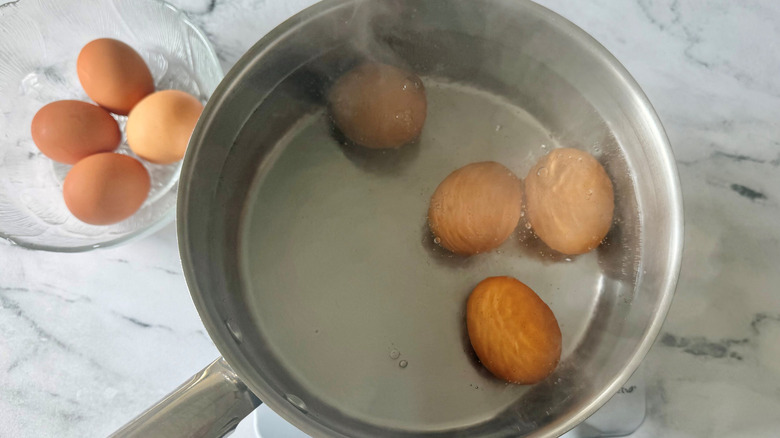 Eggs in bowl next to eggs in pot of water
