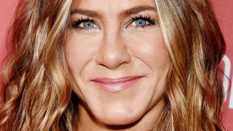 Jennifer Aniston with hair down in waves and slight smile