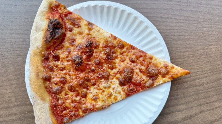 A slice of New York pizza on a paper plate