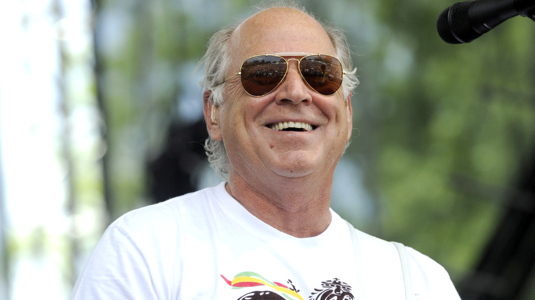Closeup of a smiling Jimmy Buffett performing in shades and a white t-shirt