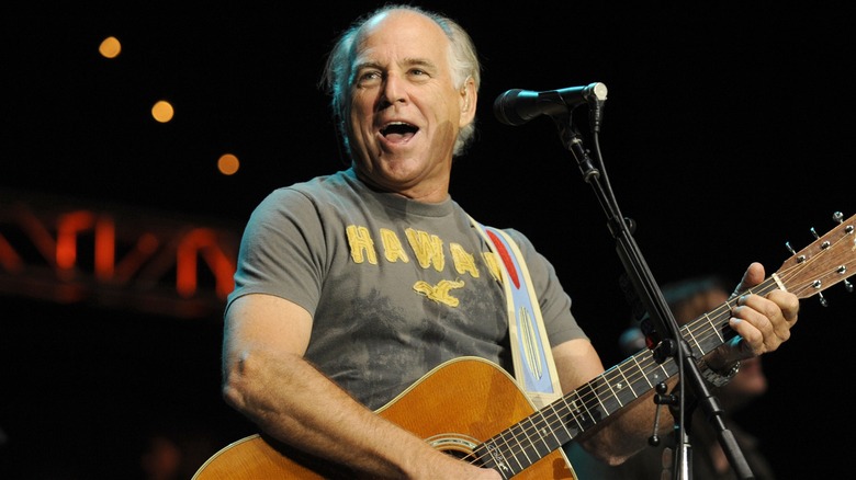 Jimmy Buffett playing an acoustic guitar on stage