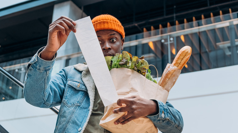 person holding grocery bag looking at receipt