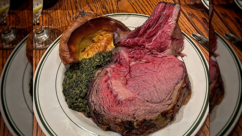 Prime rib, creamed spinach, and Yorkshire pudding on a plate