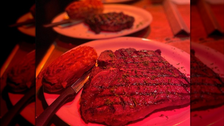 Steaks and potatoes plated in a dimly lit restaurant