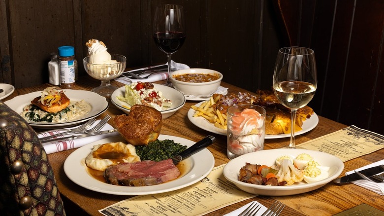 A table with two entrees, salad, wine, and side dishes