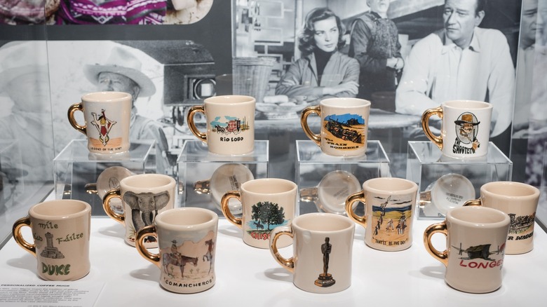 John Wayne gold-handled gift mugs on display in museum.