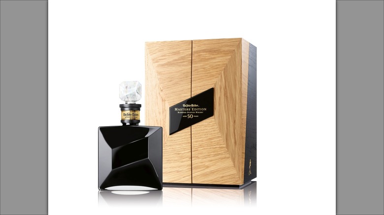 Black bottle of John Walker Masters' Edition next to wooden case with nameplate.
