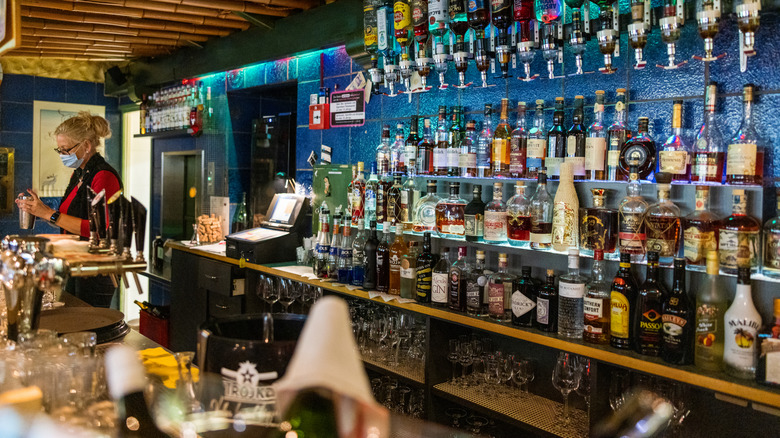 A woman works at a cluttered bar