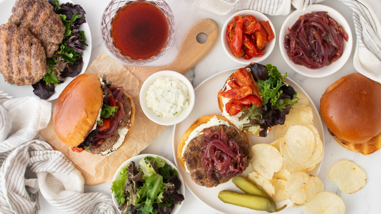 Lamb burgers served with various toppings and potato chips