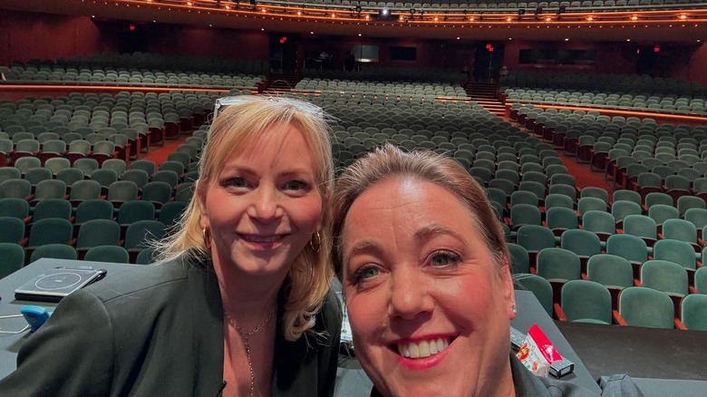 Bridget Lancaster and Julia Collin Davison smile in front of empty theater seats