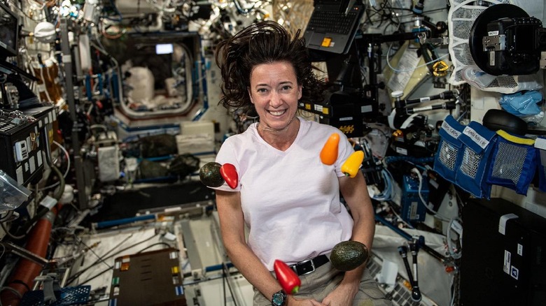 Astronaut Megan McArthur on the ISS smiling with floating vegetables