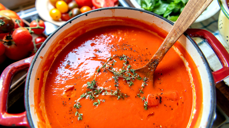Pot of homemade tomato soup with wooden spoon.