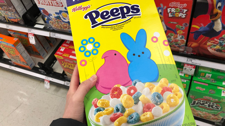 person holding a box of Kellogg's Peeps cereal in a store aisle