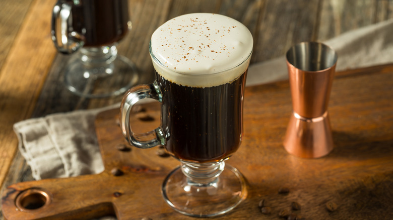 Coffee with creamy head in clear cup next to jigger