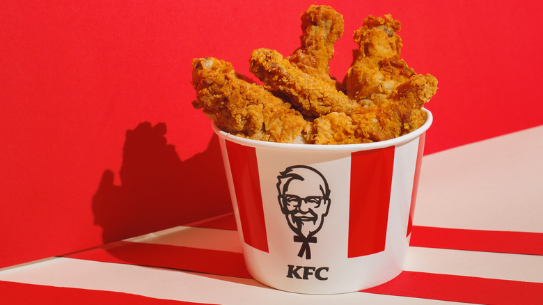 Bucket of KFC fried chicken against red wall