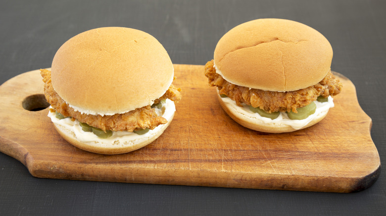 Two chicken sandwiches on wooden board