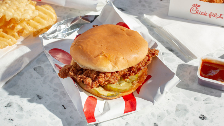 Chick-fil-A chicken sandwich surrounded by sauce and waffle fries