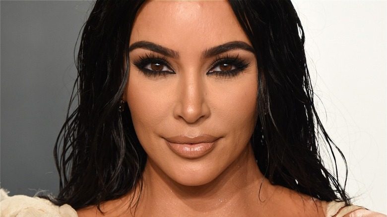 Kim Kardashian smiling on white and gray background