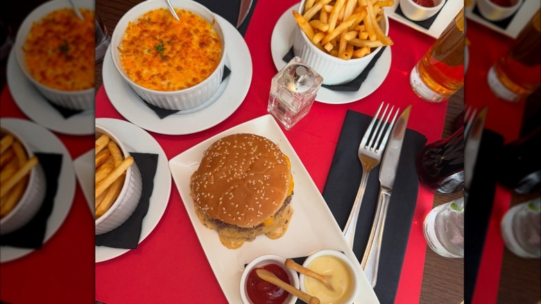 Ferdi cheeseburger, mac and cheese, and fries on red table