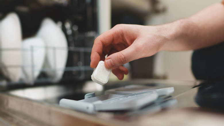 Hand putting dishwasher tablet in dishwasher