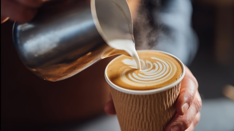 Barista pouring steamed milk into a latte.