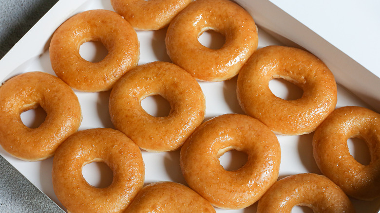 A dozen Original Glazed Krispy Kreme doughnut sitting in a box
