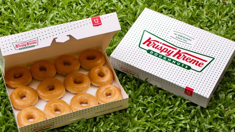 Two boxes of Krispy Kreme donuts on a bed of grass