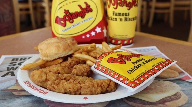 Bojangles tenders, fries, and biscuit on a plate with a drink cup.