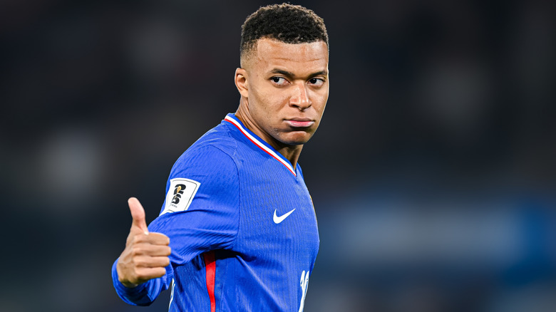 French soccer player Kylian Mbappé giving the thumbs-up on the field during a game