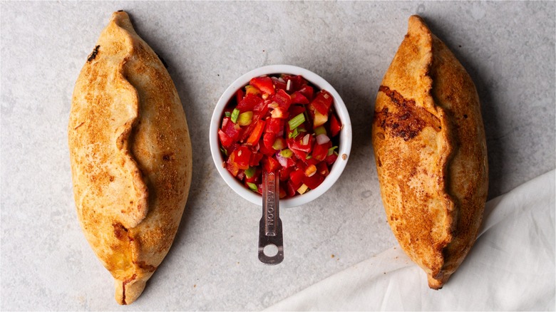 Pico de gallo in a bowl between two empanadas