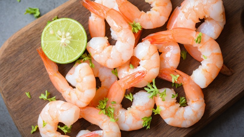 cooked shrimp with lime and parsley on a wood board