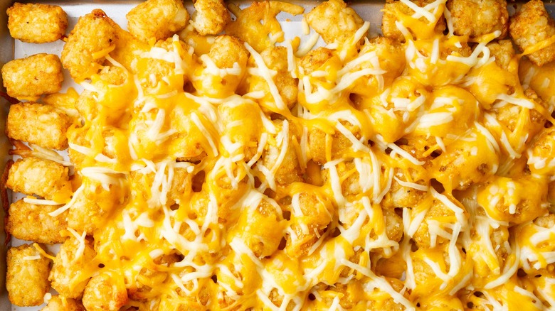 tater tots covered in cheese on baking sheet