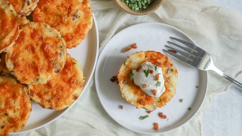 Loaded mashed potato cup on plate next to more servings on larger plate