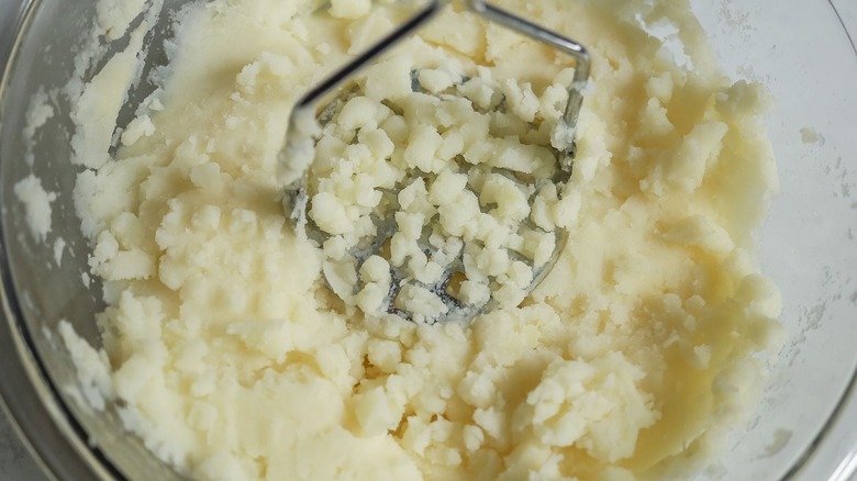 Potato masher mashing potatoes in bowl